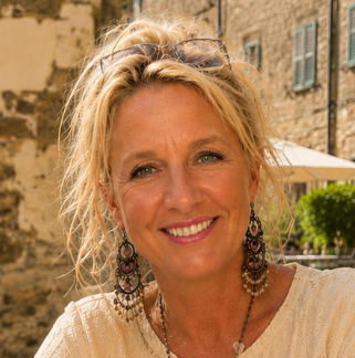 Wendy, oprichtster van Puur Kroatië, glimlachend op een zonnige locatie met een natuurstenen muur op de achtergrond.